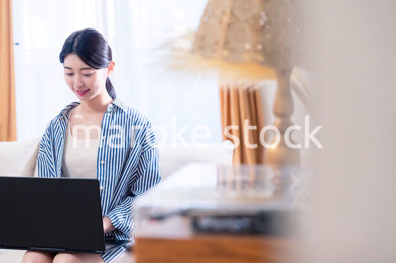 家でリラックスをしてパソコンを使う若い女性