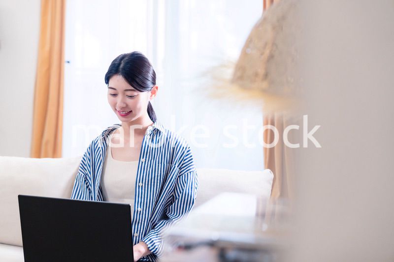 家でリラックスをしてパソコンを使う若い女性