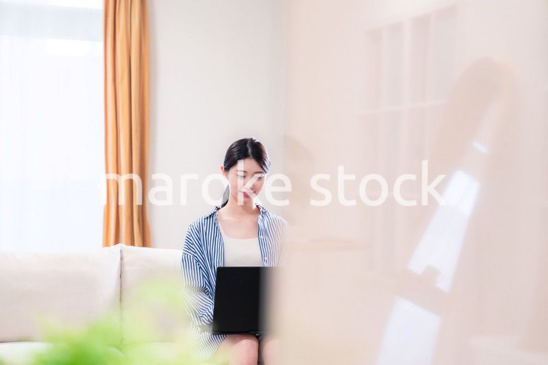 家でリラックスをしてパソコンを使う若い女性