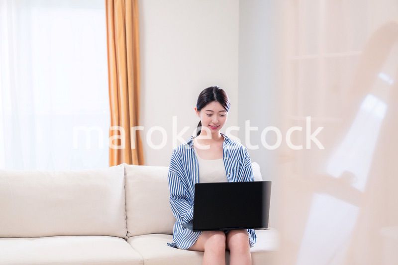 家でリラックスをしてパソコンを使う若い女性