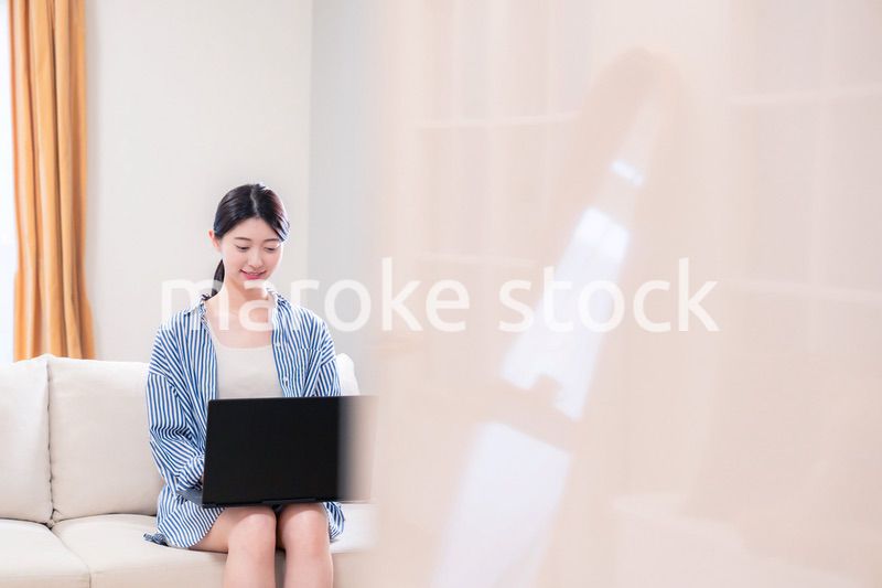 家でリラックスをしてパソコンを使う若い女性
