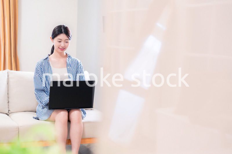 家でリラックスをしてパソコンを使う若い女性