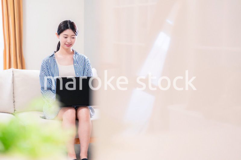 家でリラックスをしてパソコンを使う若い女性