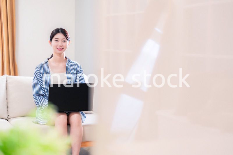 家でリラックスをしてパソコンを使う若い女性