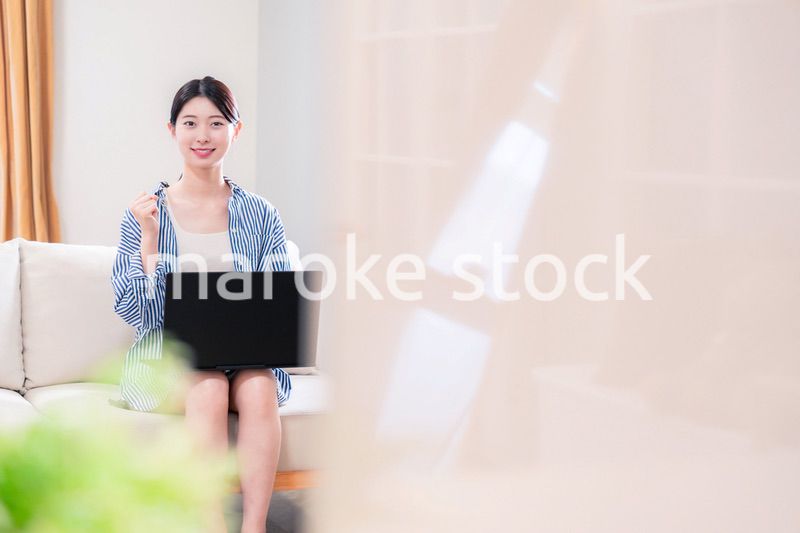 家でリラックスをしてパソコンを使う若い女性