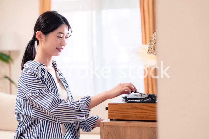 家でレコードを聴く若い女性