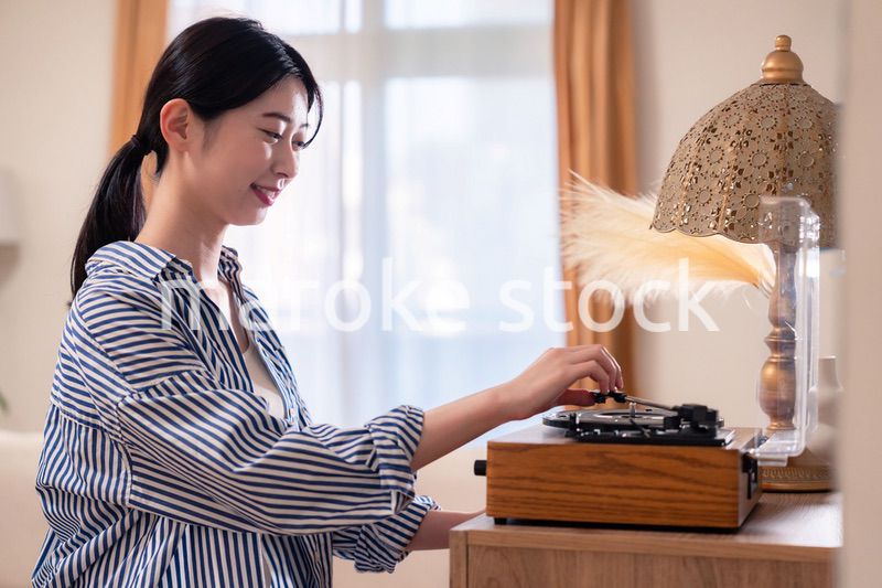 家でレコードを聴く若い女性