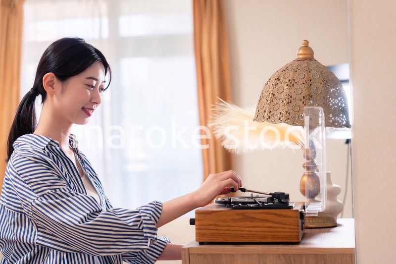 家でレコードを聴く若い女性