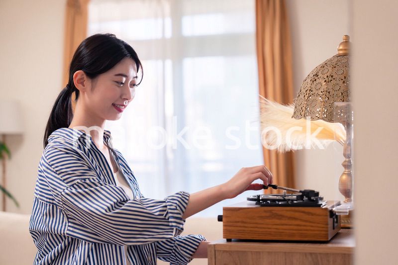 家でレコードを聴く若い女性