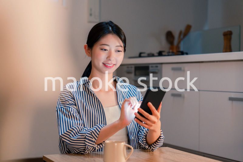 夜遅くに笑顔でスマホを使う若い女性