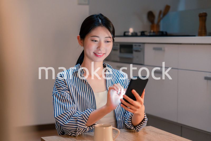 夜遅くに笑顔でスマホを使う若い女性