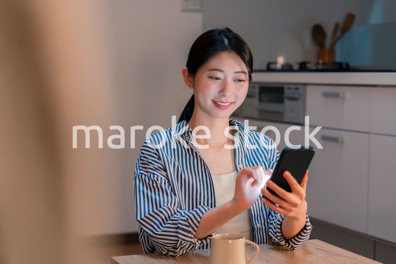 夜遅くに笑顔でスマホを使う若い女性