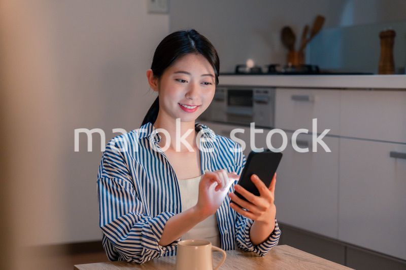 夜遅くに笑顔でスマホを使う若い女性
