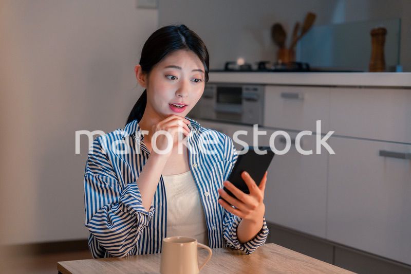 夜遅くに笑顔でスマホを使う若い女性