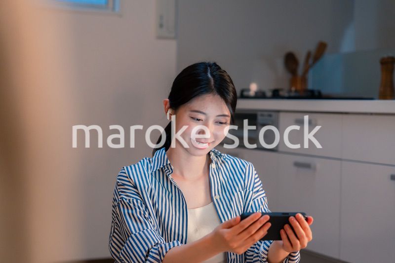 夜にスマホでコンテンツを楽しむ一人暮らしの女性
