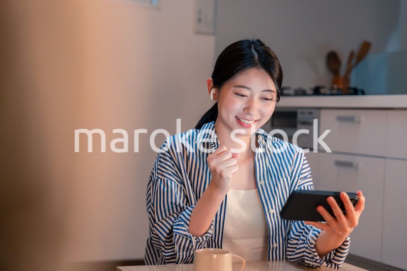 夜に家でスマホでスポーツ観戦をする若い女性