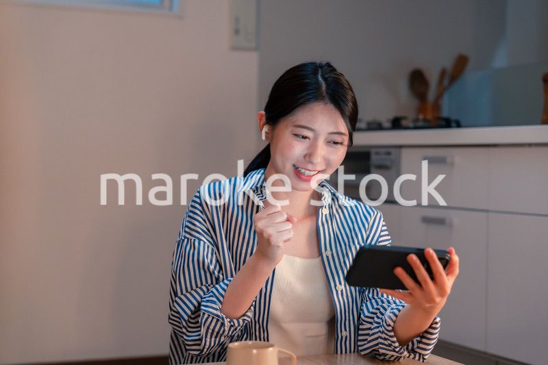 夜に家でスマホでスポーツ観戦をする若い女性