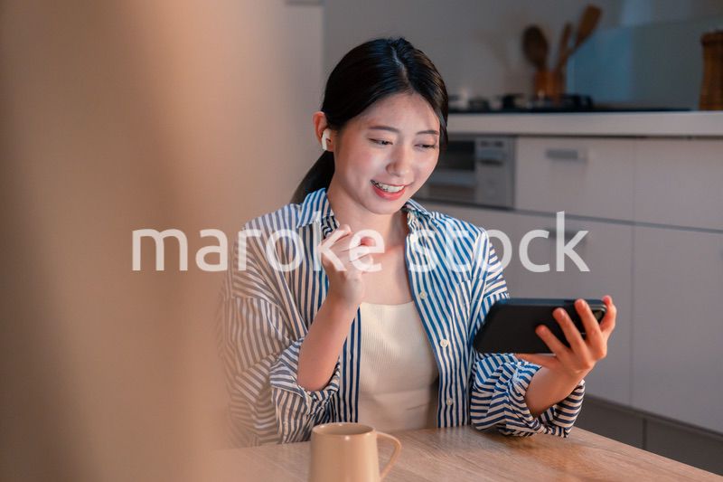 夜に家でスマホでスポーツ観戦をする若い女性