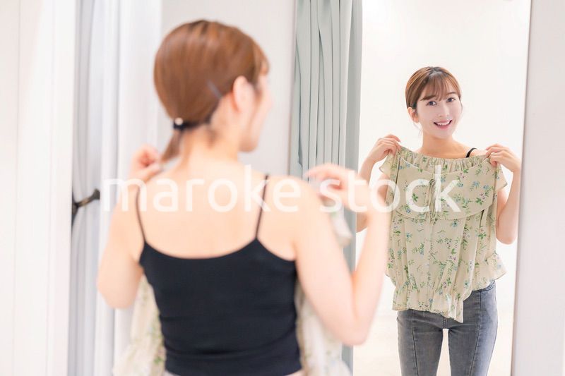 試着室で服の試着をする若い女性