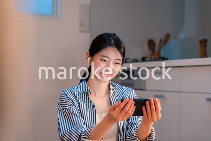 夜にスマホでコンテンツを楽しむ一人暮らしの女性