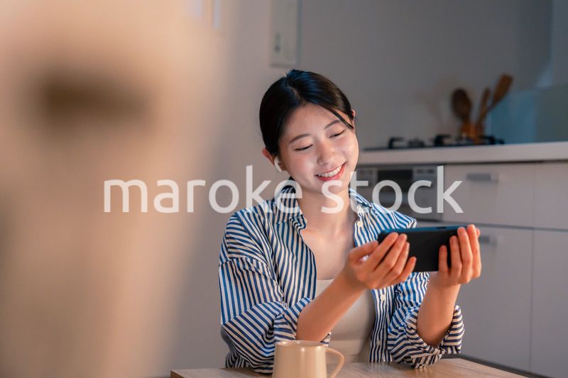 夜にスマホでコンテンツを楽しむ一人暮らしの女性