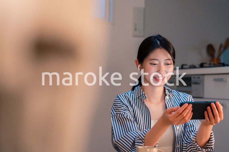 夜にスマホでコンテンツを楽しむ一人暮らしの女性