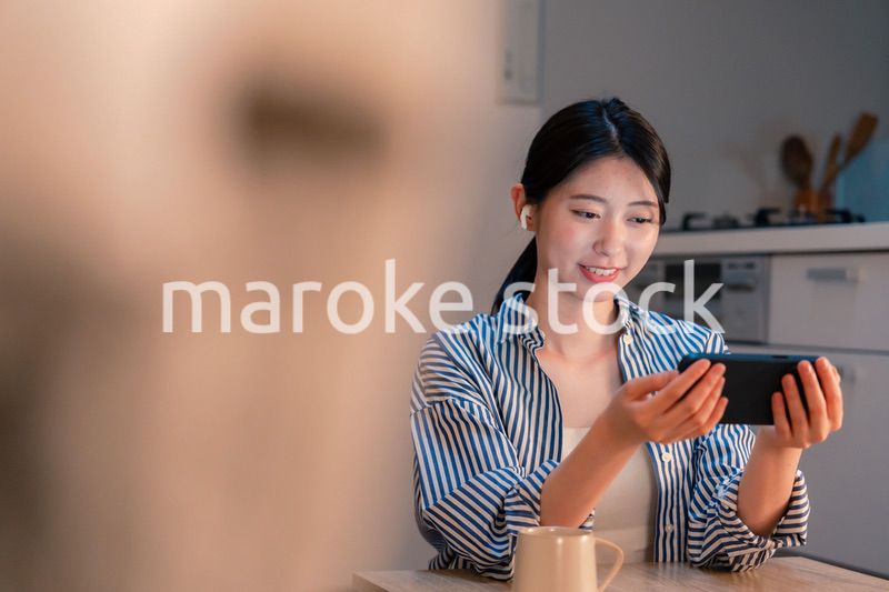 夜にスマホでコンテンツを楽しむ一人暮らしの女性