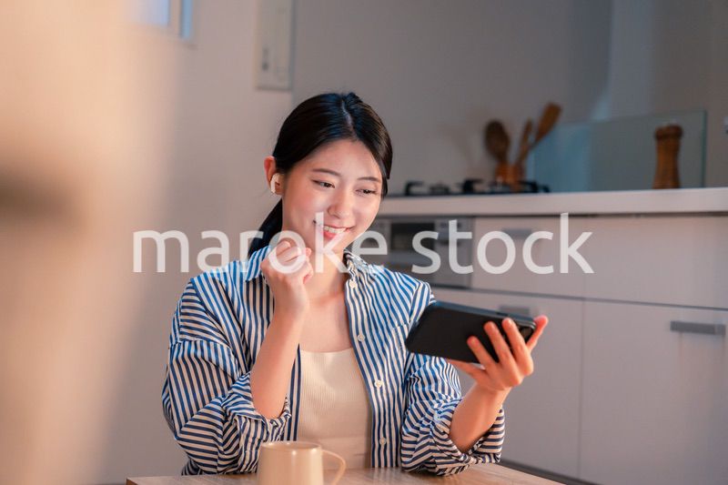 夜に家でスマホでスポーツ観戦をする若い女性