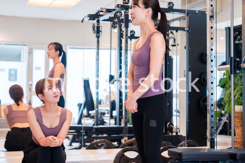 ジムで運動をしながら楽しく話をする女性