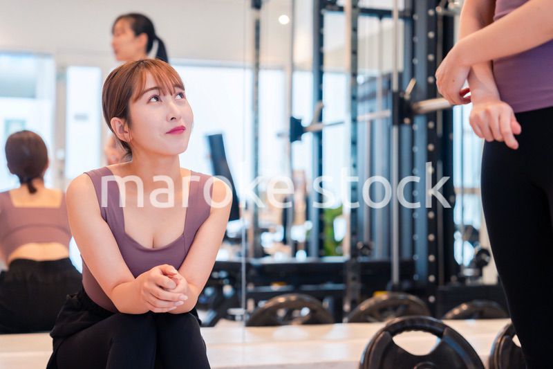 ジムで運動をしながら楽しく話をする女性