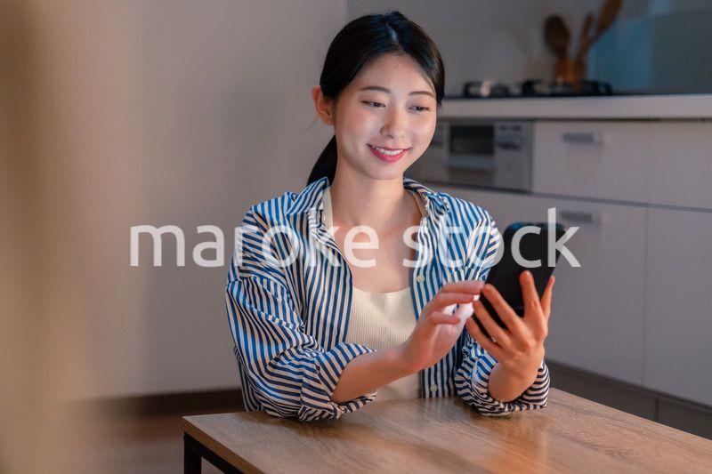 夜遅くに笑顔でスマホを使う若い女性