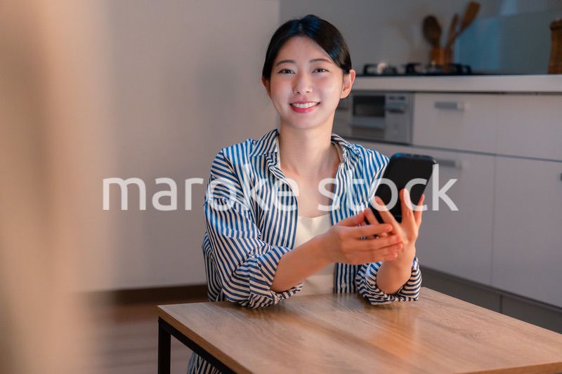夜遅くに笑顔でスマホを使う若い女性