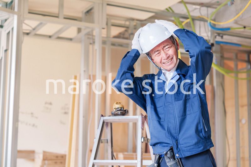 現場で頭を抱える男性の大工