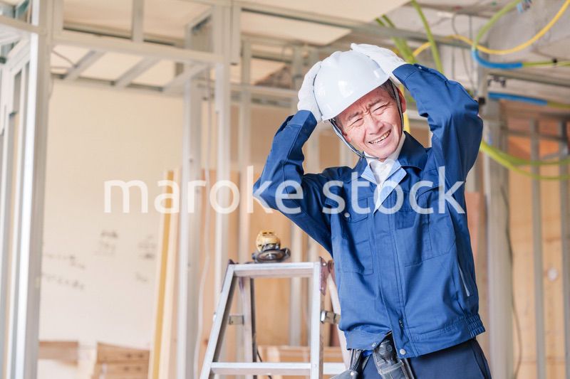 現場で頭を抱える男性の大工