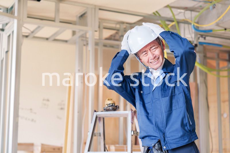 現場で頭を抱える男性の大工