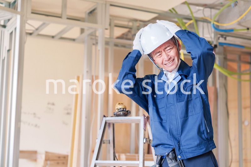 現場で頭を抱える男性の大工