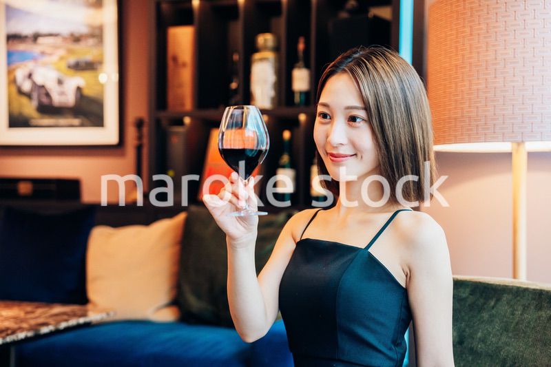 ラグジュアリーな雰囲気のお店で赤ワインを飲む若い女性