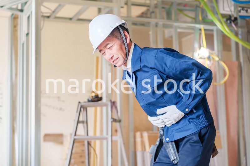 現場で腹痛に苦しむ男性の大工