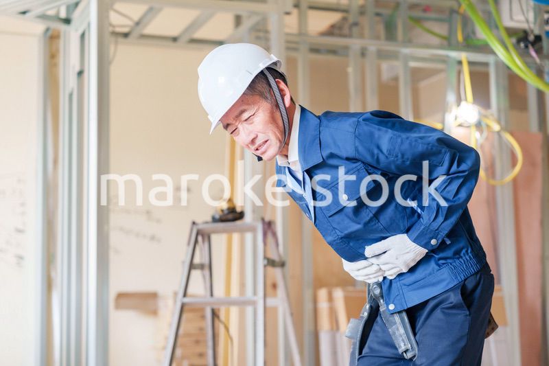 現場で腹痛に苦しむ男性の大工