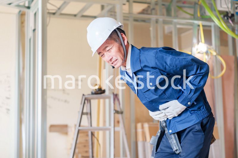 現場で腹痛に苦しむ男性の大工