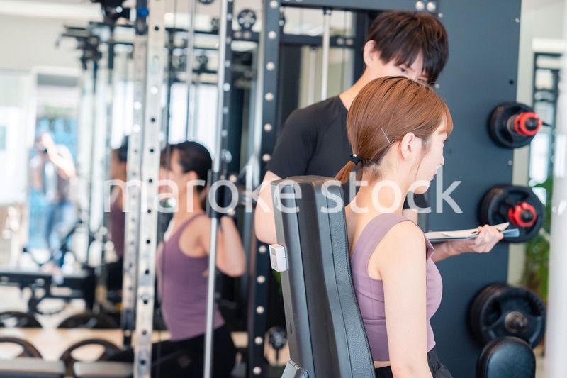 ジムのマシーンでトレーニングをする人