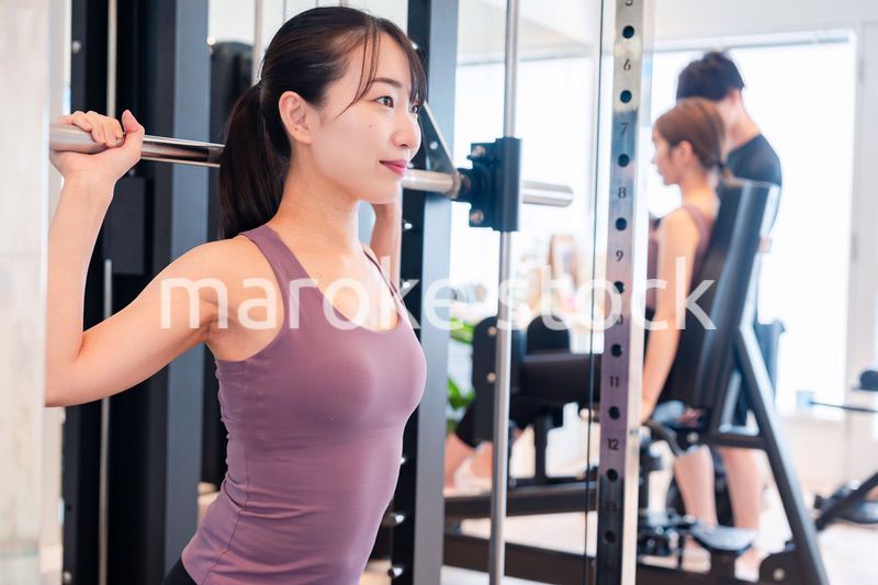 ジムのマシーンでトレーニングをする人