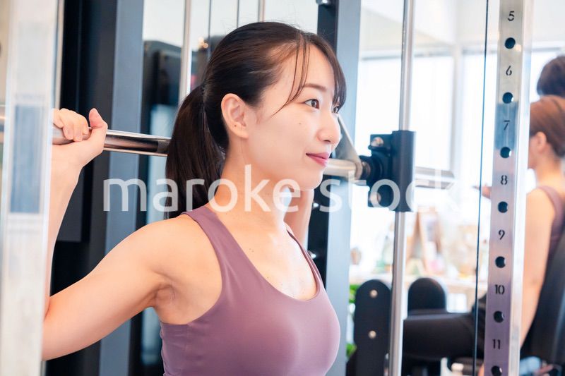 ジムのマシーンでトレーニングをする人