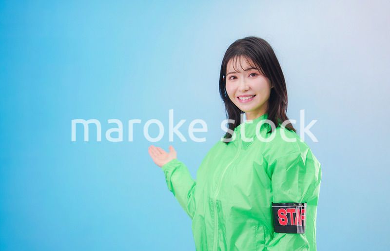 笑顔でお客様を案内するイベントスタッフ（水色背景）