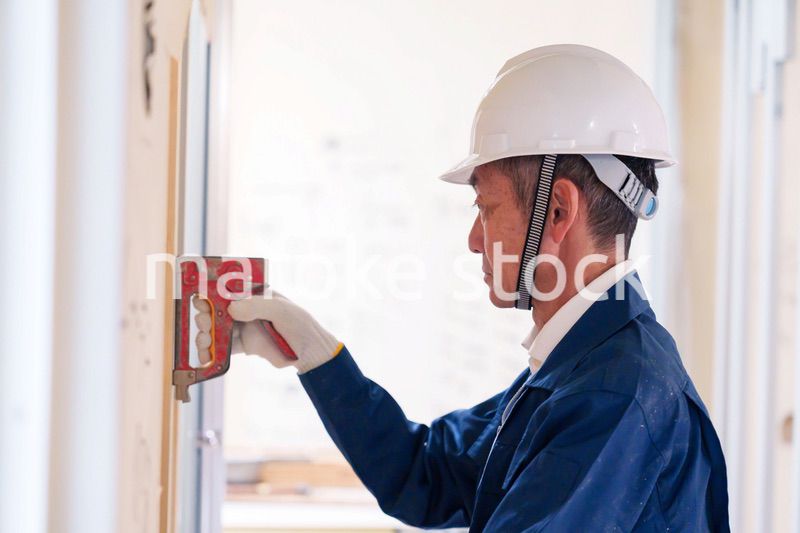 タッカーで建築資材を固定する男性の職人