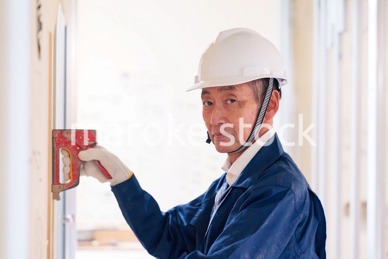 タッカーで建築資材を固定する男性の職人