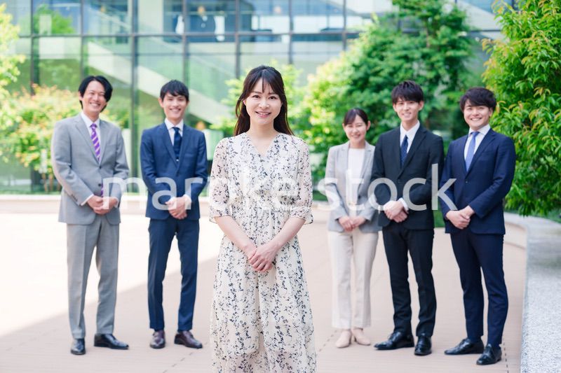 オフィス街に立つ若い女性キャリアウーマンとスタッフ