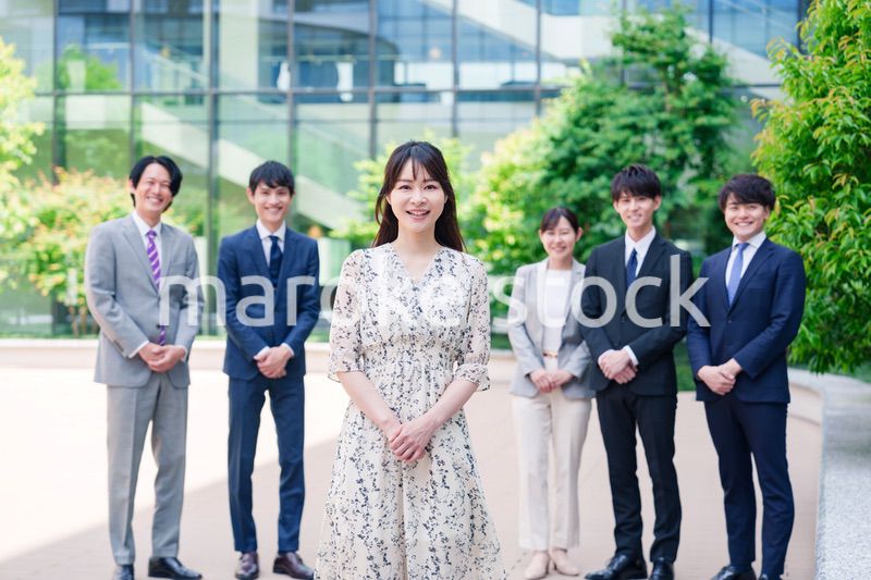 オフィス街に立つ若い女性キャリアウーマンとスタッフ