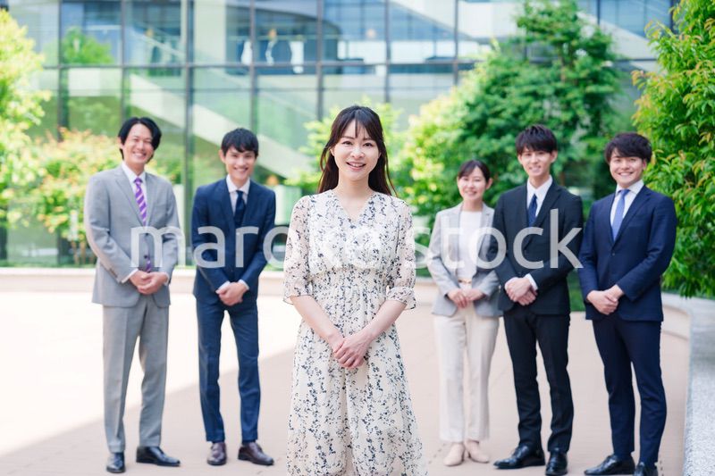 オフィス街に立つ若い女性キャリアウーマンとスタッフ