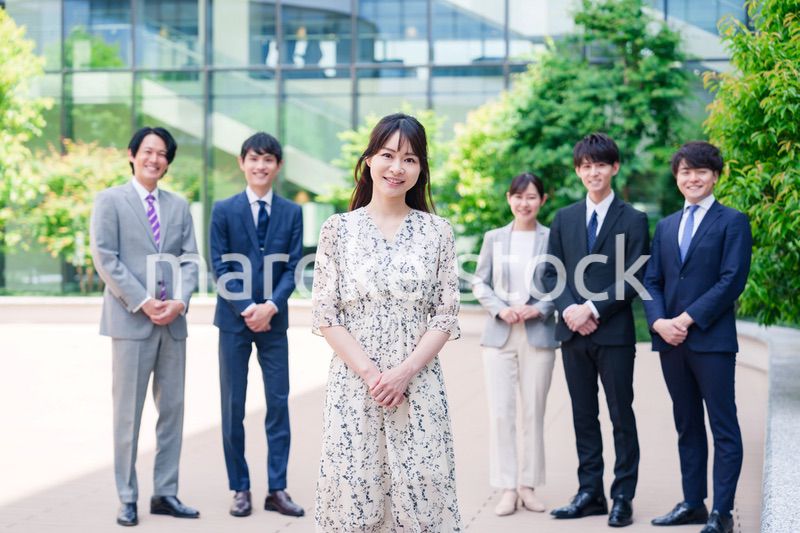 オフィス街に立つ若い女性キャリアウーマンとスタッフ